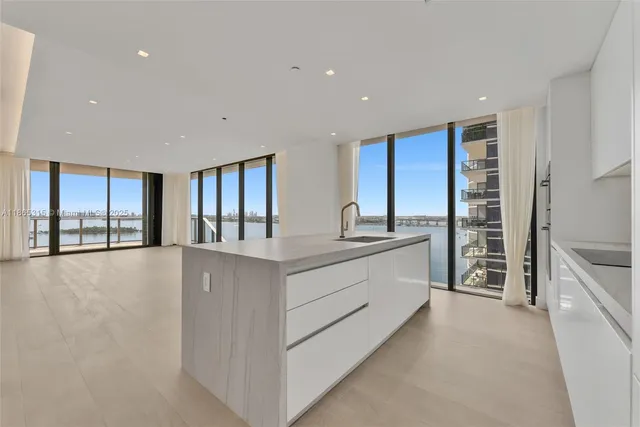 a large white kitchen with granite countertop a large window and a sink