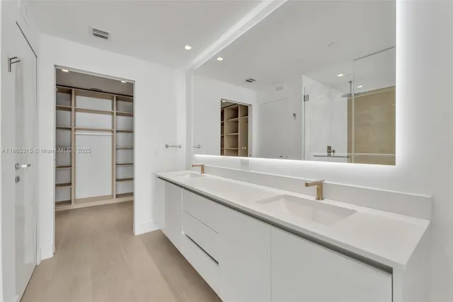 a bathroom with a double vanity sink a mirror and a shower