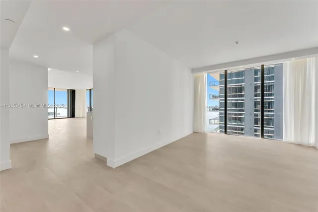 a view of an empty room with a window and kitchen view