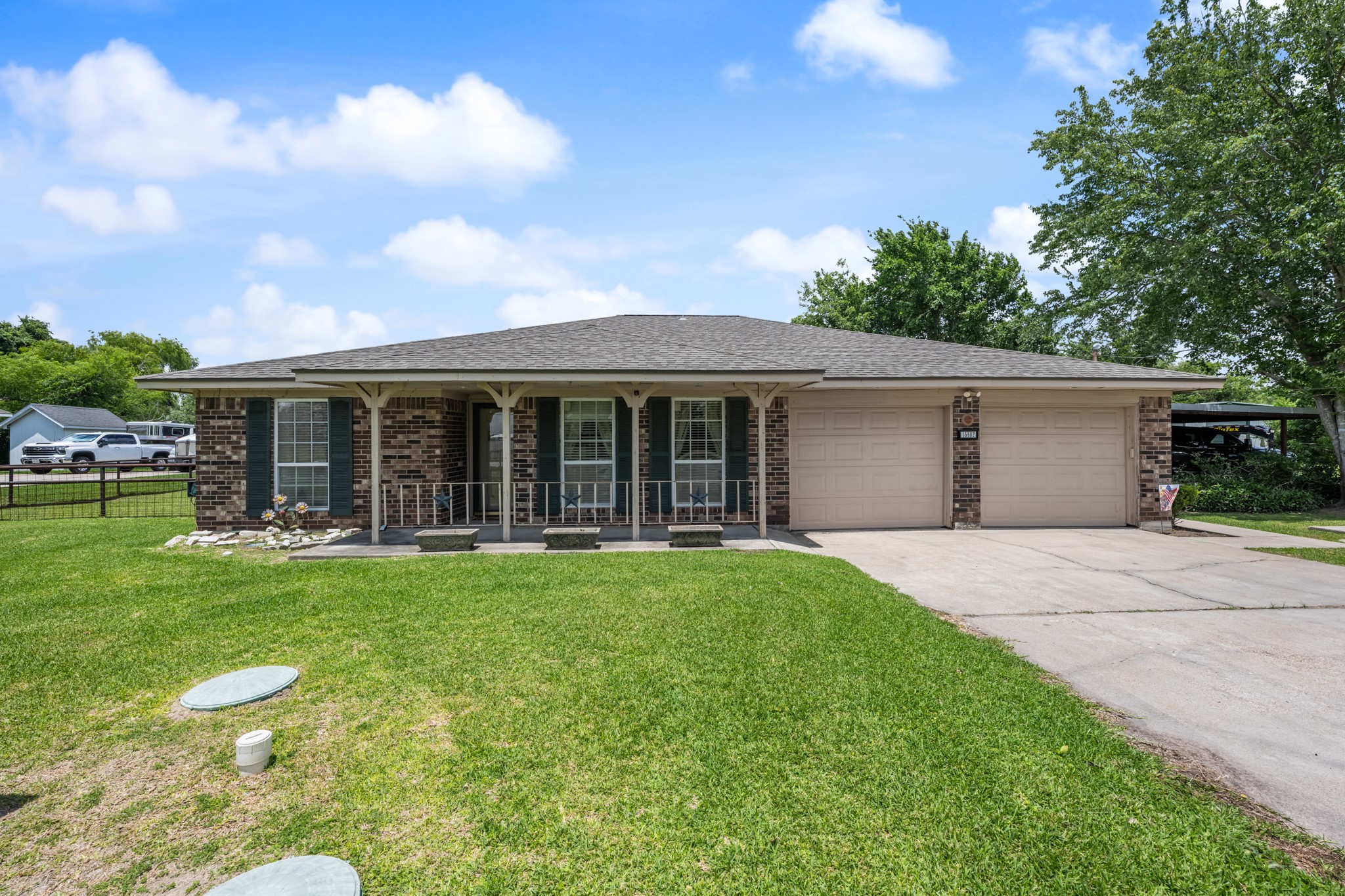 15602 Fir Road Santa Fe, TX 77517 - Photo 2 of 42 Charming single-story brick home featuring a welcoming covered front porch, mature shade trees, and an expansive front lawn. The attached two-car garage and additional covered parking provide added convenience and functionality.