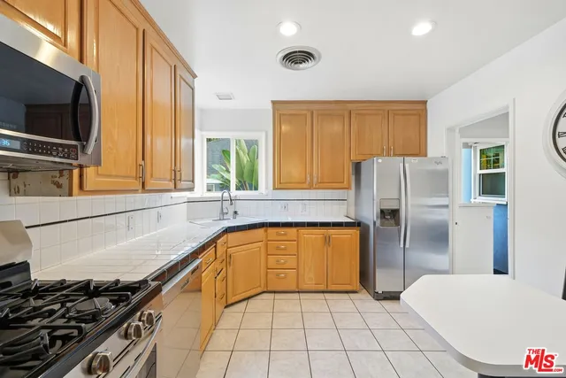 a kitchen with stainless steel appliances granite countertop a sink a stove a refrigerator a washer dryer and cabinets