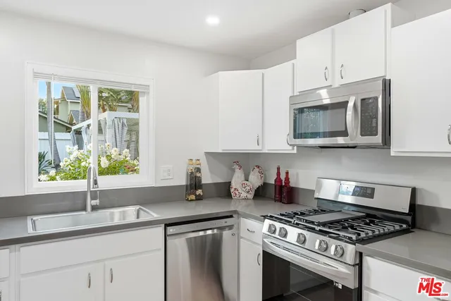 a kitchen with granite countertop appliances a sink cabinets and a window