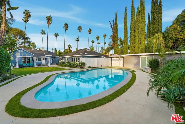 a view of swimming pool with lawn chairs under an umbrella
