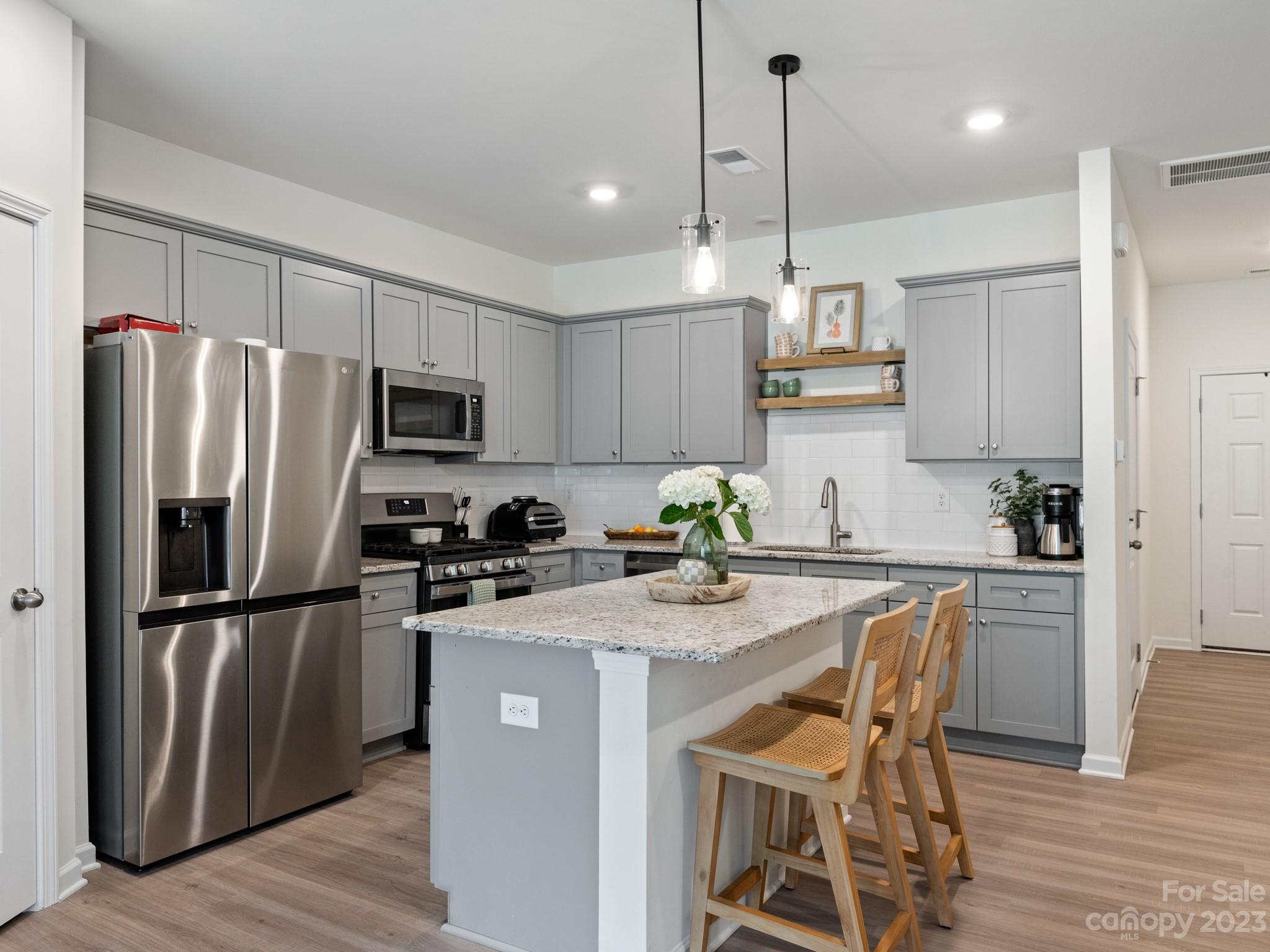 225 Quinn Road Matthews, NC 28104 - Photo 7 of 24 a kitchen with stainless steel appliances granite countertop a refrigerator a stove a sink dishwasher a microwave oven with cabinets and wooden floor