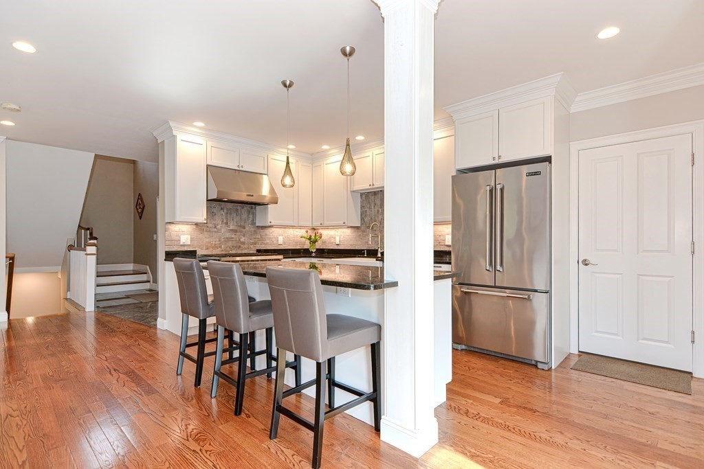 89 Walker Street, Unit 89 Newton, MA 02460 - Photo 11 of 42 a kitchen with stainless steel appliances granite countertop a refrigerator a stove a dining table and chairs with wooden floor