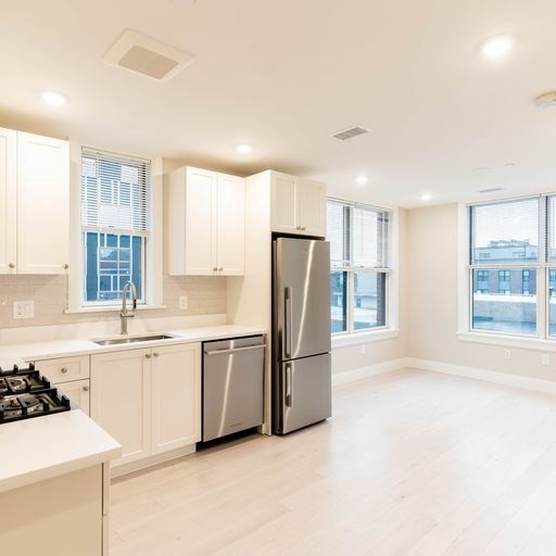197 Green Street, Unit 305 Boston, MA 02130 - Photo 4 of 7 a kitchen with stainless steel appliances a refrigerator sink and cabinets