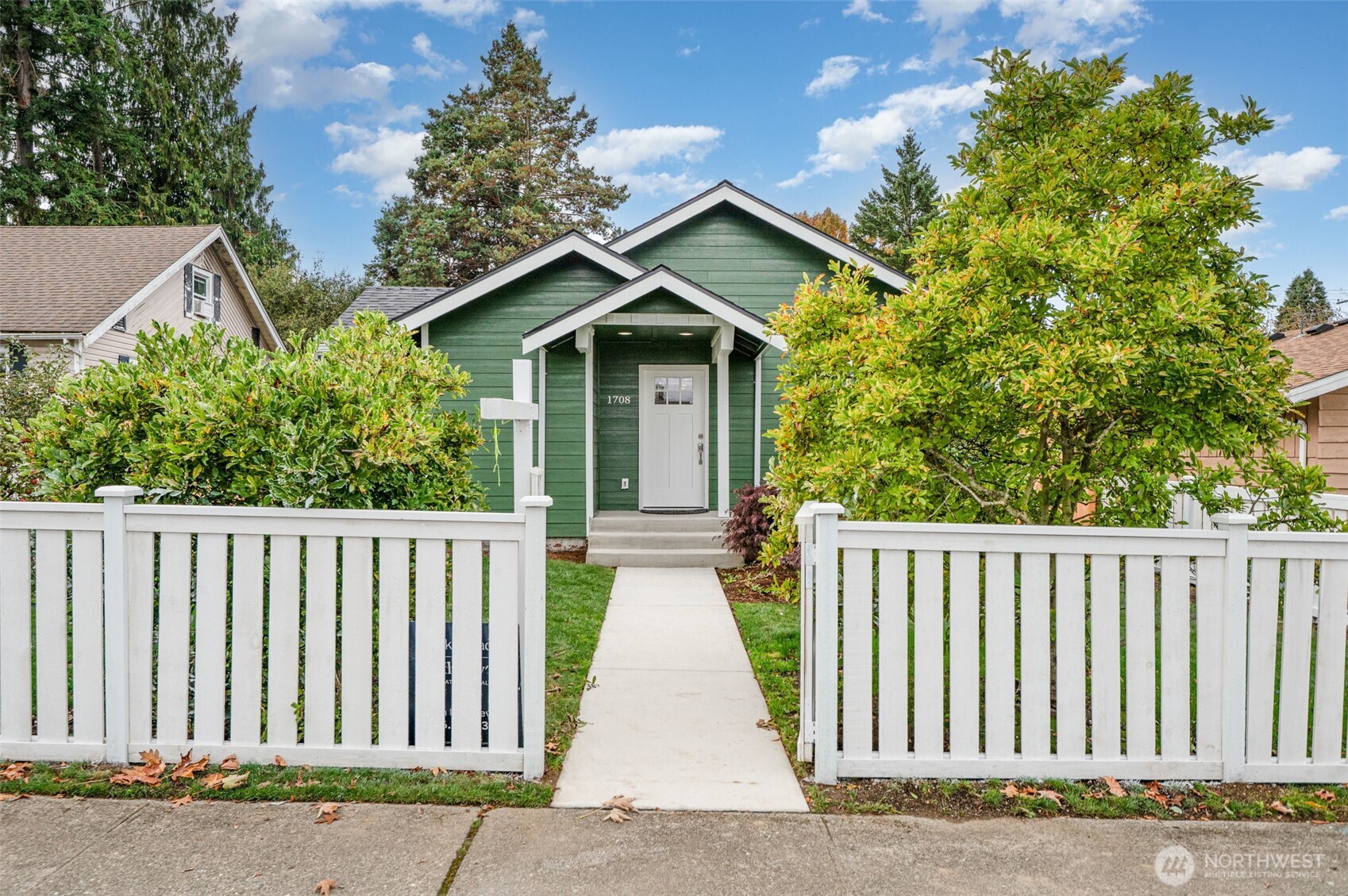 a view of a house with a small yard plants and large trees