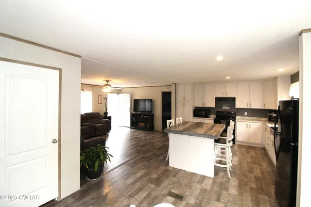 a living room with couches and kitchen view with wooden floor