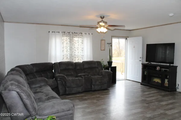 a living room with furniture a flat screen tv and a window