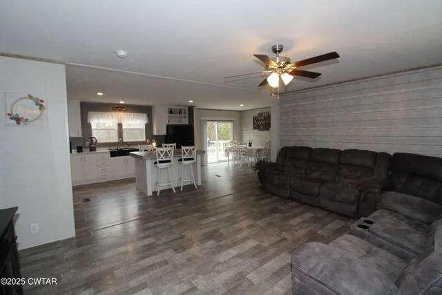 a living room with couches and kitchen view with wooden floor