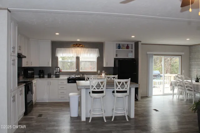 a kitchen with stainless steel appliances granite countertop a stove top oven a sink dishwasher a dining table and chairs with wooden floor