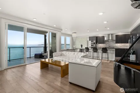 a living room with stainless steel appliances kitchen island granite countertop a large window and a counter space
