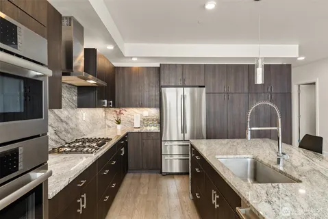 a kitchen with stainless steel appliances granite countertop a sink stove and refrigerator