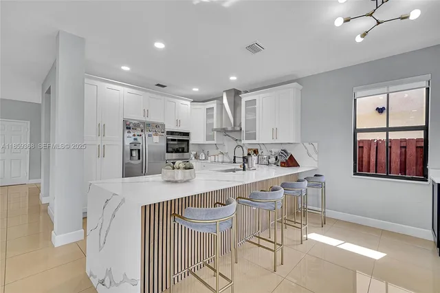 a large white kitchen with a sink and refrigerator