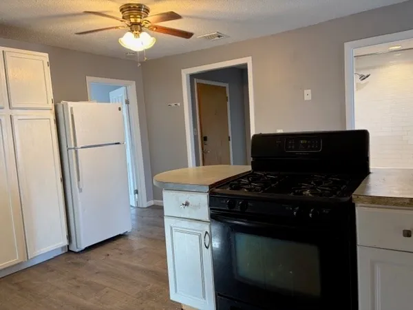 a view of a hallway with wooden floor and a kitchen