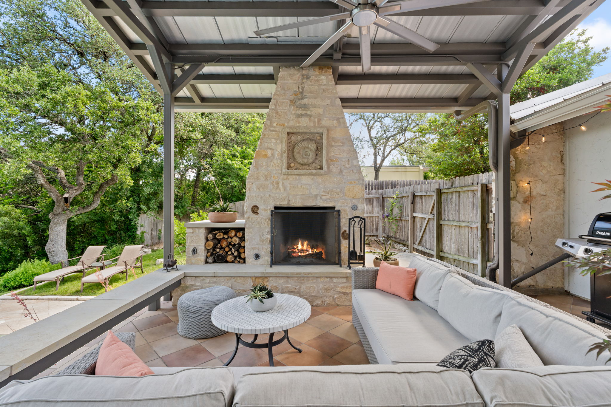 2310 Camino Alto Road Austin, TX 78746 - Photo 27 of 29 a view of a patio with a dining table and chairs with a fireplace