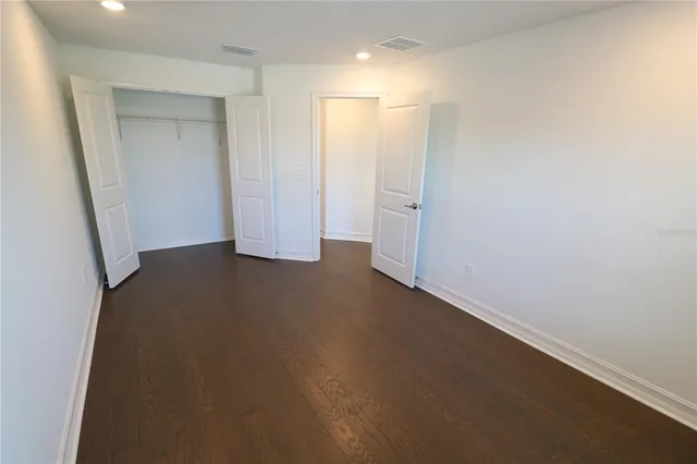 an empty room with wooden floor and cabinet