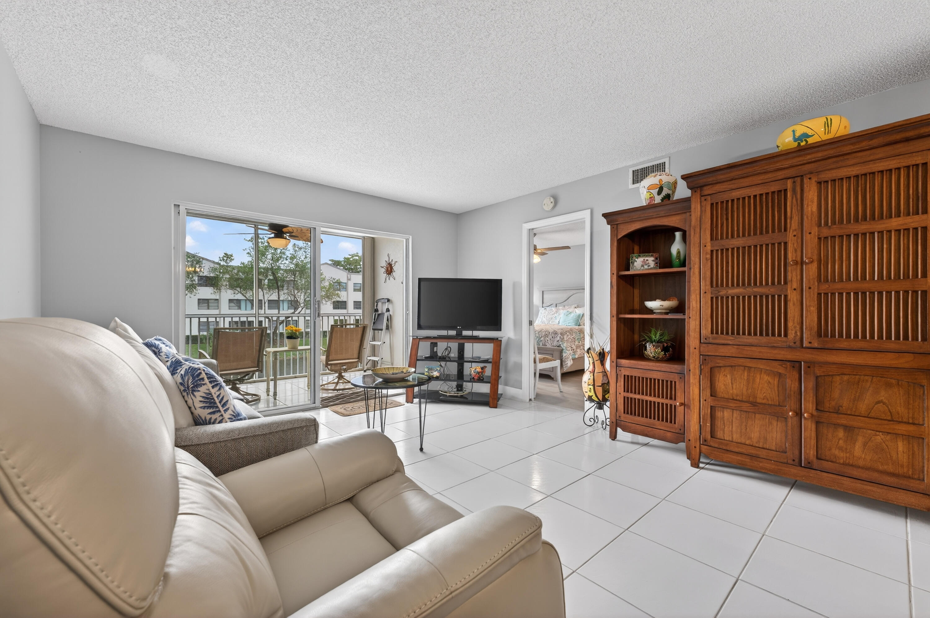 7142 South Devon Drive, Unit 210 Tamarac, FL 33321 - Photo 12 of 36 a living room with furniture a flat screen tv and floor to ceiling window