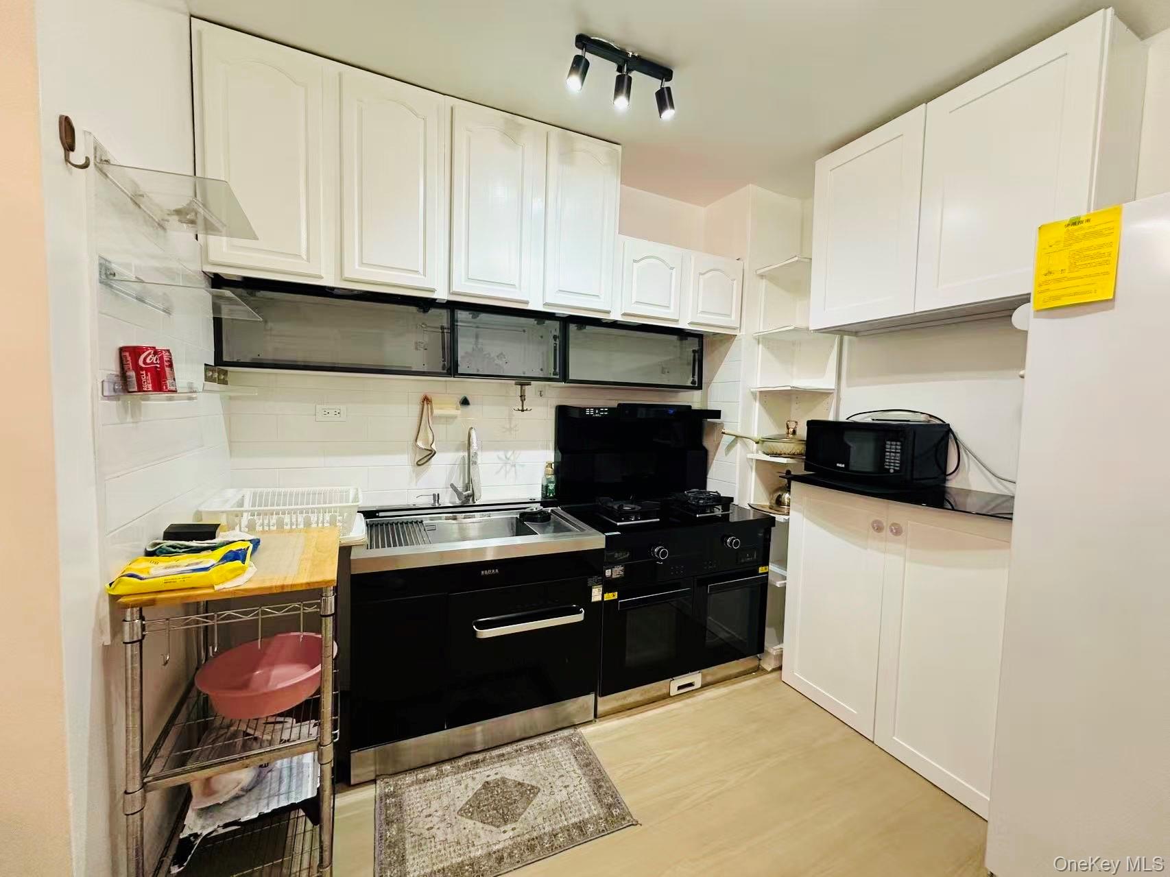 64-74 Saunders Street, Unit 2D Queens, NY 11374 - Photo 2 of 10 a kitchen with stainless steel appliances a stove a sink and a refrigerator