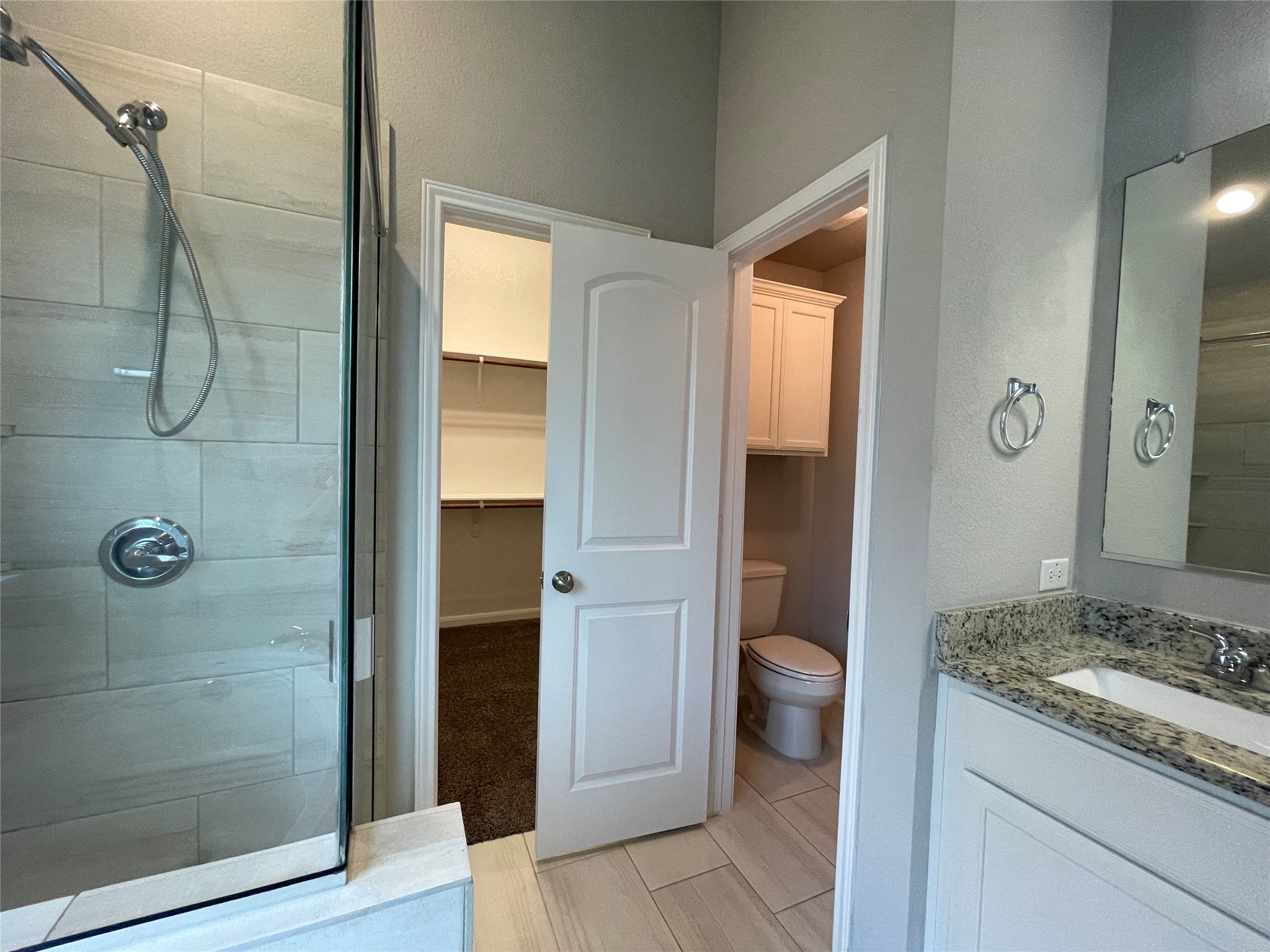 8113 Northgate Loop Temple, TX 76502 - Photo 19 of 35 Contemporary bathroom featuring a glass-enclosed shower with tile surround, a single vanity with stone countertop and undermount sink, and wood-finish tile flooring