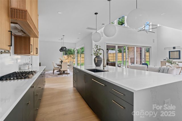 a large kitchen with stainless steel appliances a large counter top a stove and a chandelier