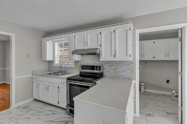 a kitchen with granite countertop a stove sink and cabinets