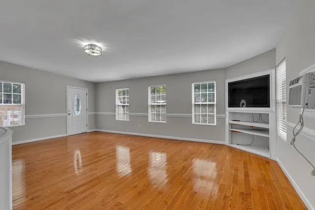 a view of an empty room with a kitchen and wooden floor