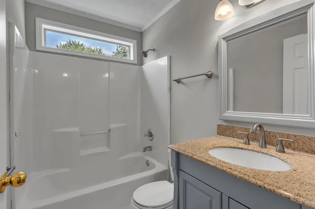a bathroom with a granite countertop toilet sink and mirror