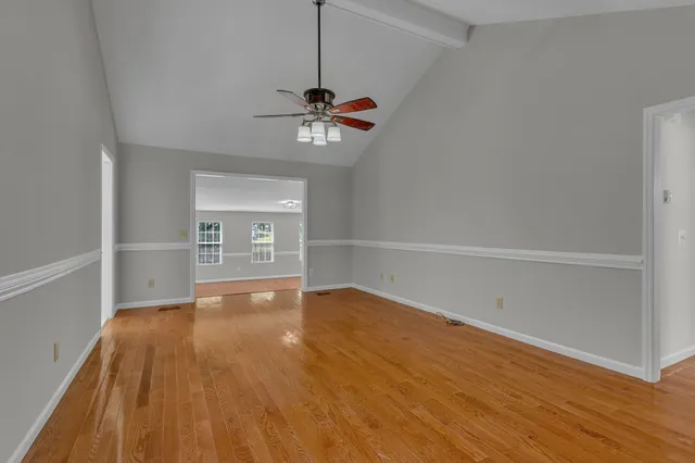 a view of empty room with wooden floor and ceiling fan