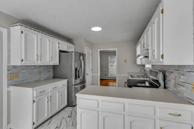 a kitchen with white cabinets and sink