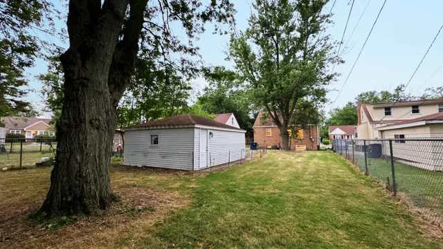 a backyard of a house with wooden fence and large trees