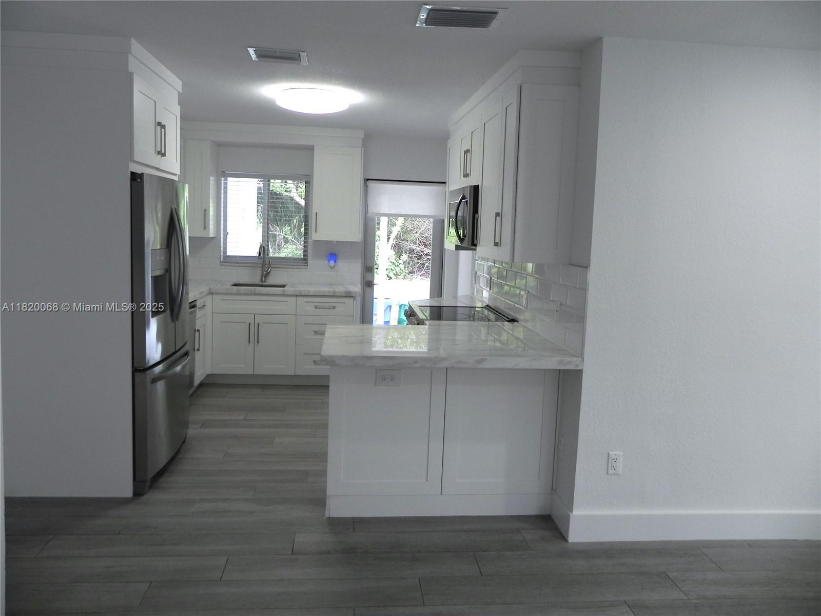 Bayside Miami, FL 33138 - Photo 12 of 44 a kitchen with stainless steel appliances granite countertop a refrigerator a sink a stove and white cabinets with wooden floor