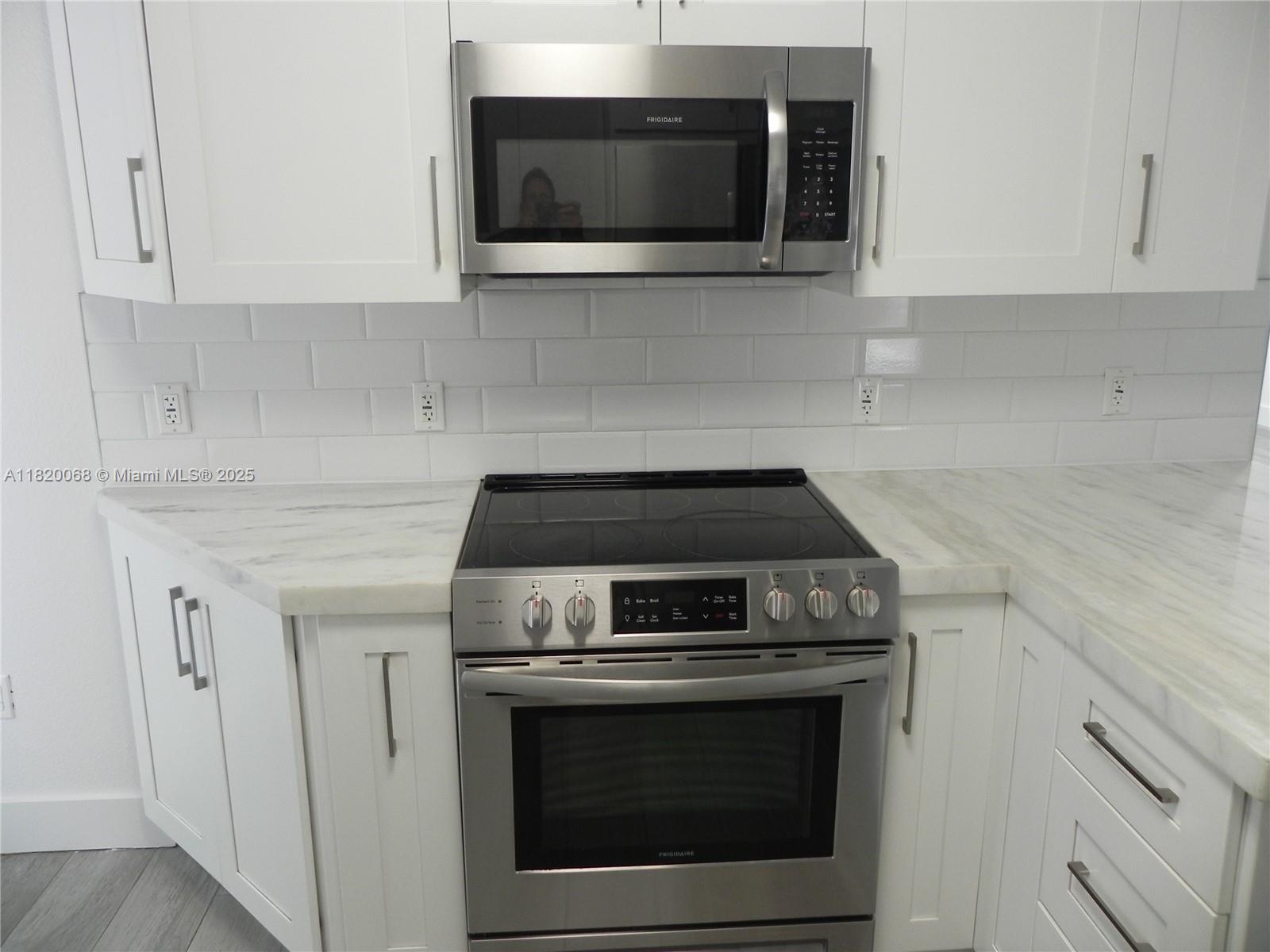 Bayside Miami, FL 33138 - Photo 14 of 44 a kitchen with granite countertop white cabinets and stainless steel appliances
