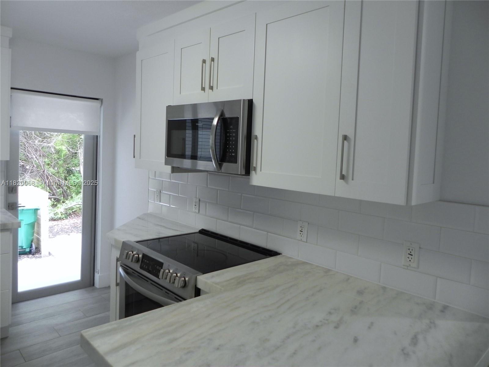 Bayside Miami, FL 33138 - Photo 15 of 44 a kitchen with stainless steel appliances a stove a microwave and cabinets