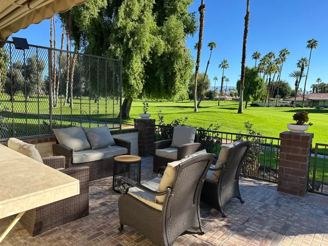 a view of a patio with couches table and chairs under an umbrella