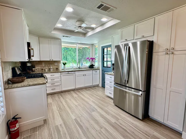 a kitchen with granite countertop a refrigerator cabinets and wooden floor
