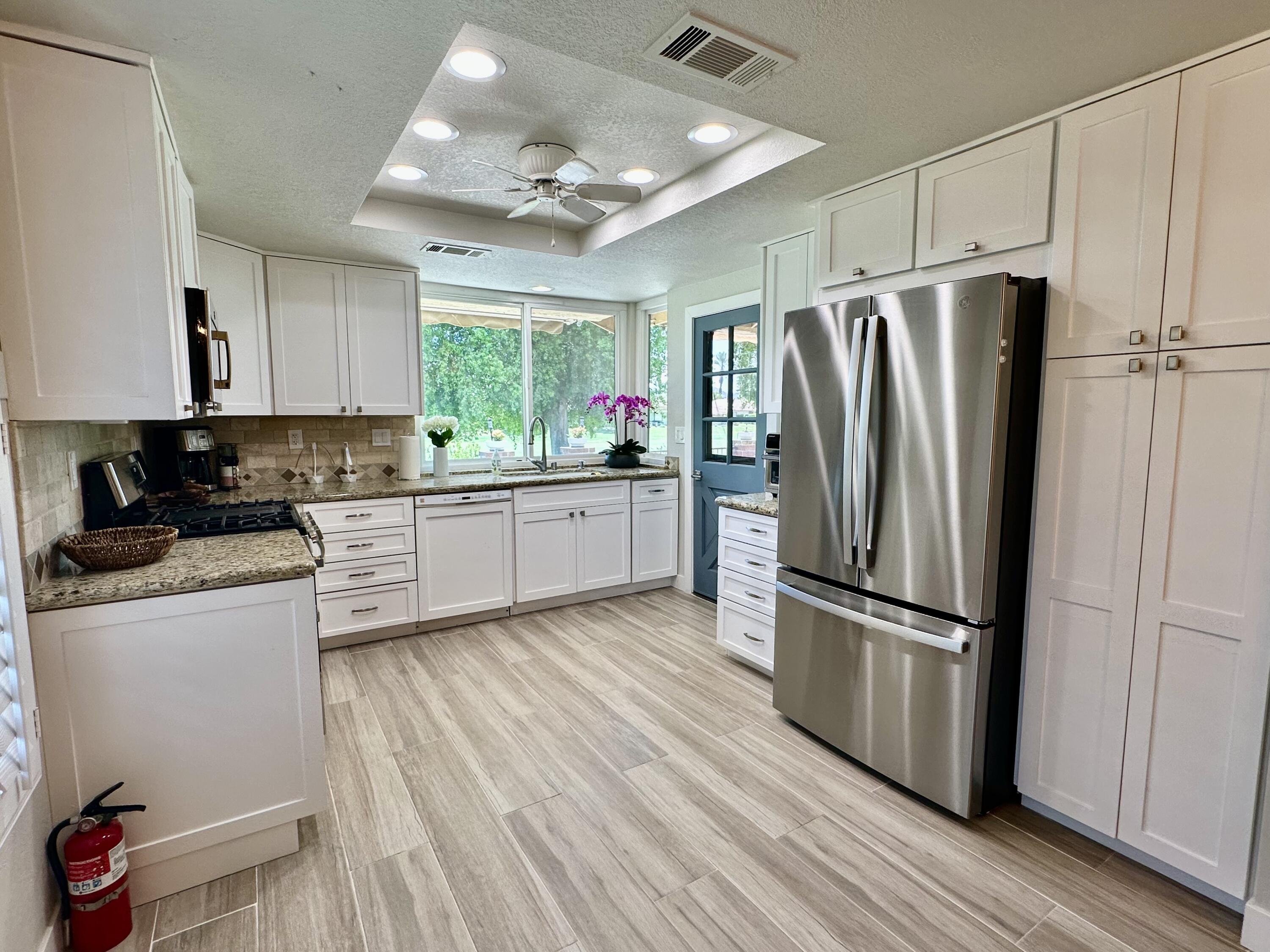 246 Santa Barbara Circle Palm Desert, CA 92260 - Photo 5 of 16 a kitchen with granite countertop a refrigerator cabinets and wooden floor