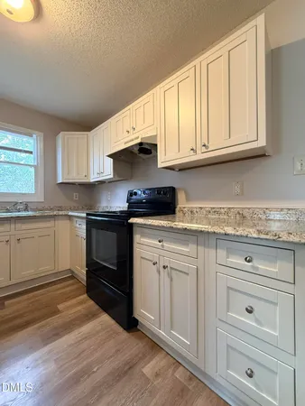 a kitchen with granite countertop white cabinets and white appliances
