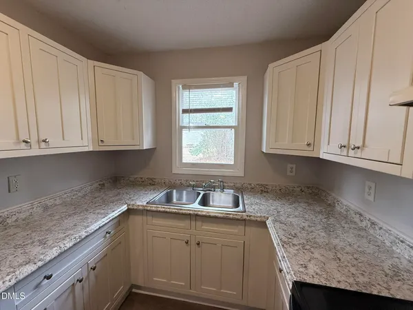 a kitchen with granite countertop white cabinets and sink