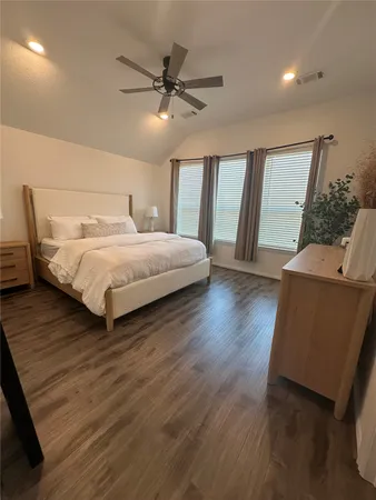 a bedroom with a bed and large mirror with wooden floor