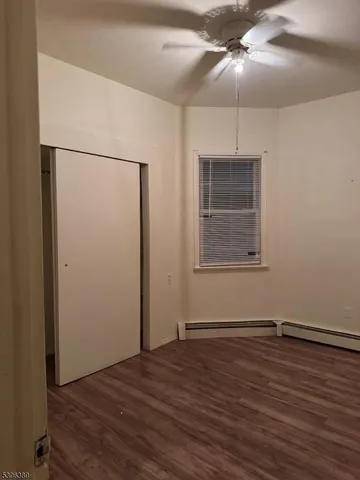 an empty room with wooden floor cabinet and windows