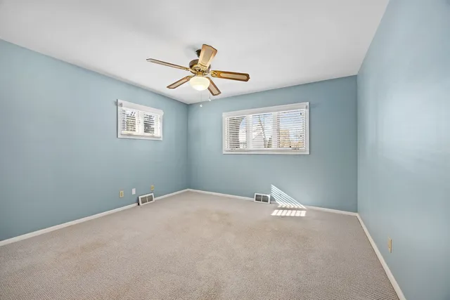 an empty room with windows and fan