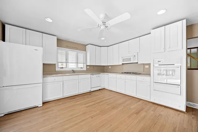 a kitchen with stainless steel appliances white cabinets and wooden floors
