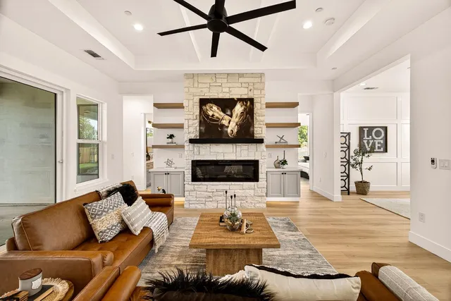 a view of a hallway to a livingroom with wooden floor and windows