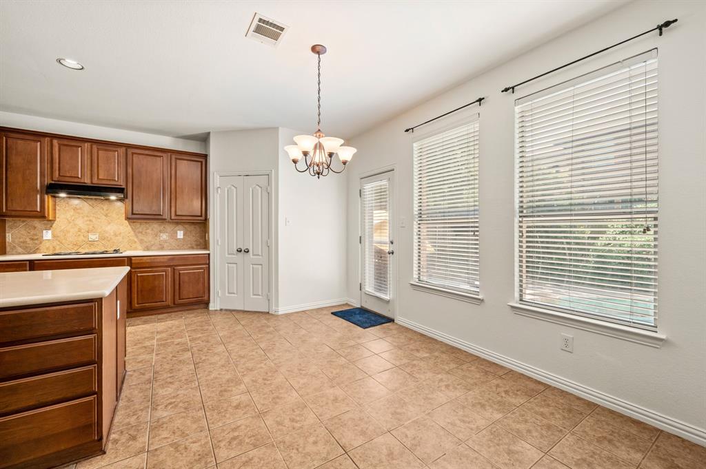 808 Briar Ridge Drive Keller, TX 76248 - Photo 12 of 40 Open concept kitchen and dining area featuring wood cabinetry, stone-finish backsplash, built-in cooktop, and a kitchen island with stone-finish countertop