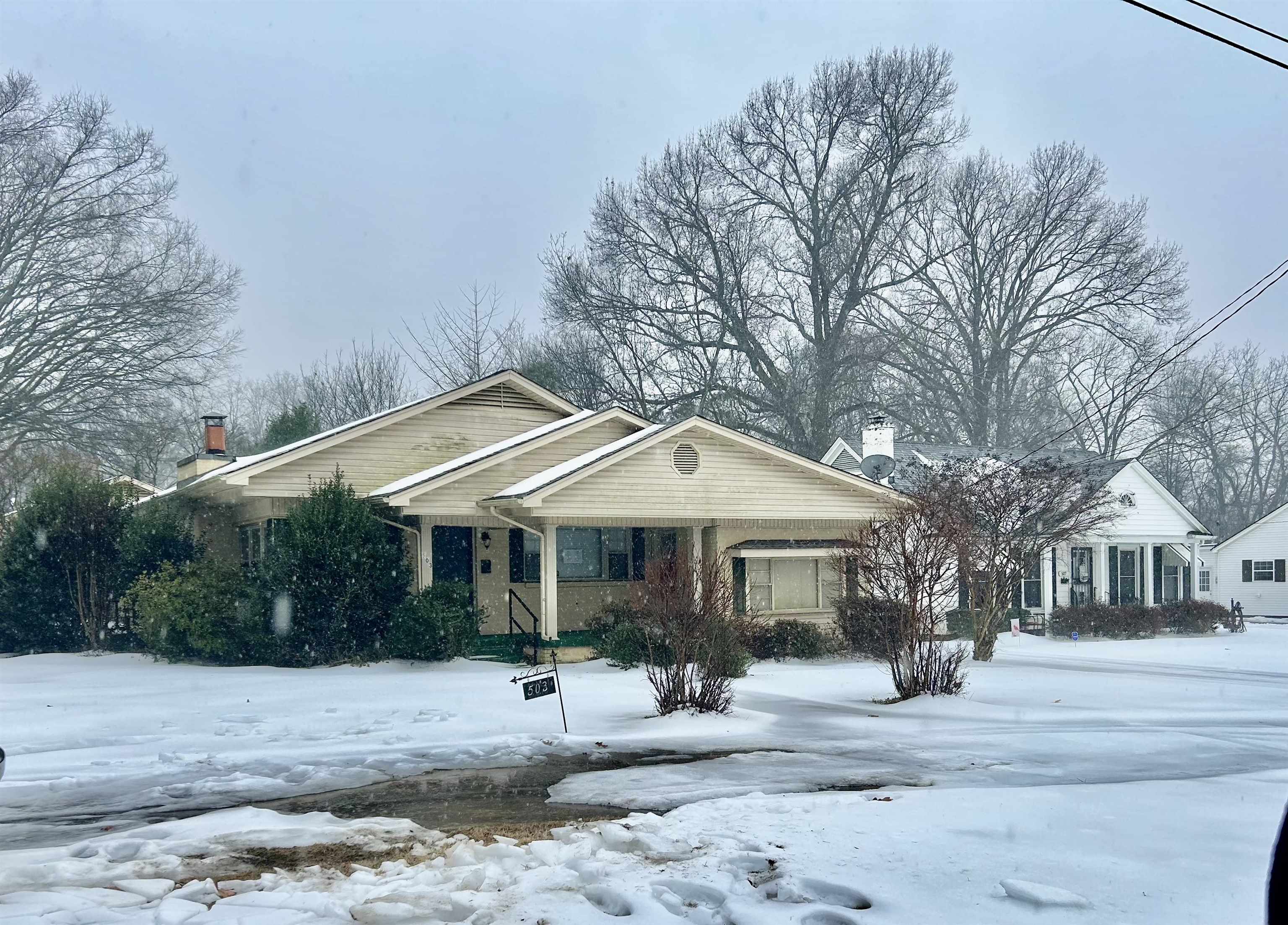 View of front of property featuring a chimney and covered porch