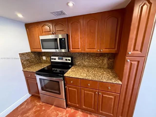 a kitchen with granite countertop wood cabinets and stainless steel appliances