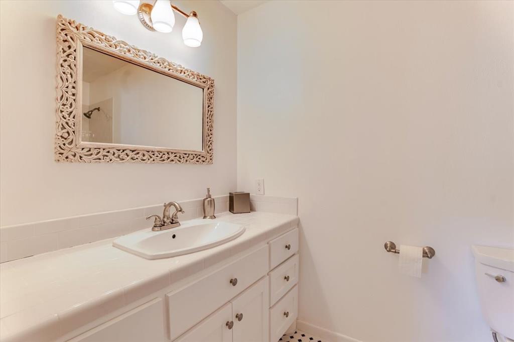 1674 Ming Bend Road Graham, TX 76450 - Photo 10 of 40 Vanity with an integrated sink, brushed nickel faucet, and a decorative carved mirror