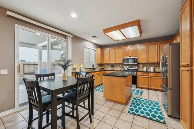 a kitchen with stainless steel appliances granite countertop a stove a sink dishwasher and a dining table with wooden floor