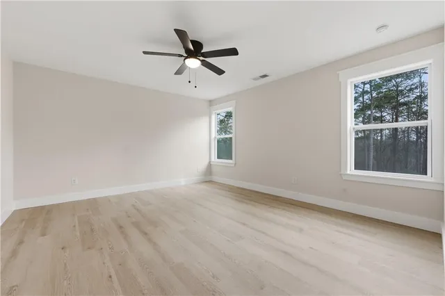 an empty room with wooden floor and ceiling fan